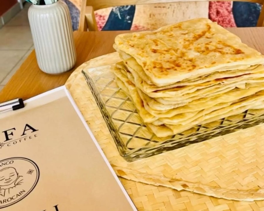 Pile de msemen dorés sur un plateau en verre, avec le menu ANFA
