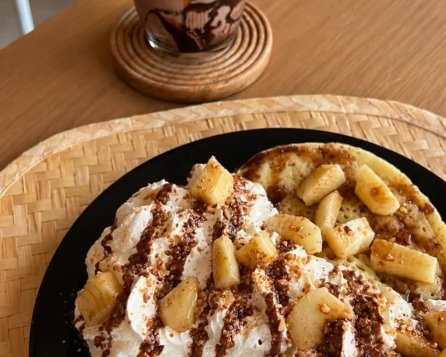 Pancakes aux bananes, crème et éclats de noisette avec un chocolat chaud