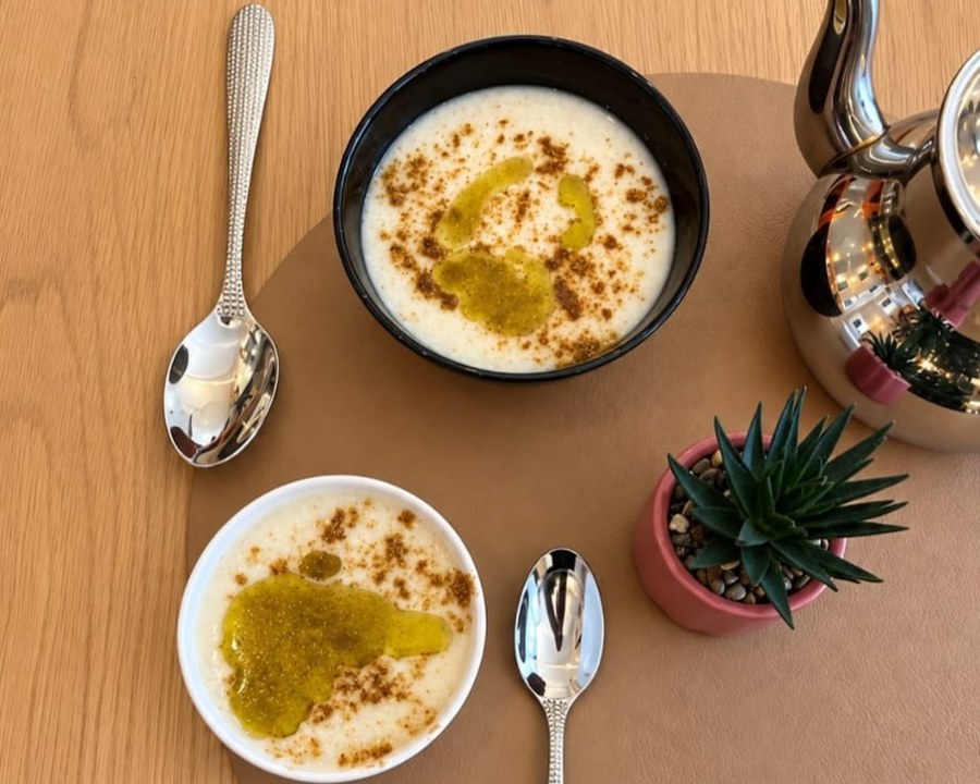 Deux bols de hassoua nappés d’huile et de cannelle, à côté d’une théière